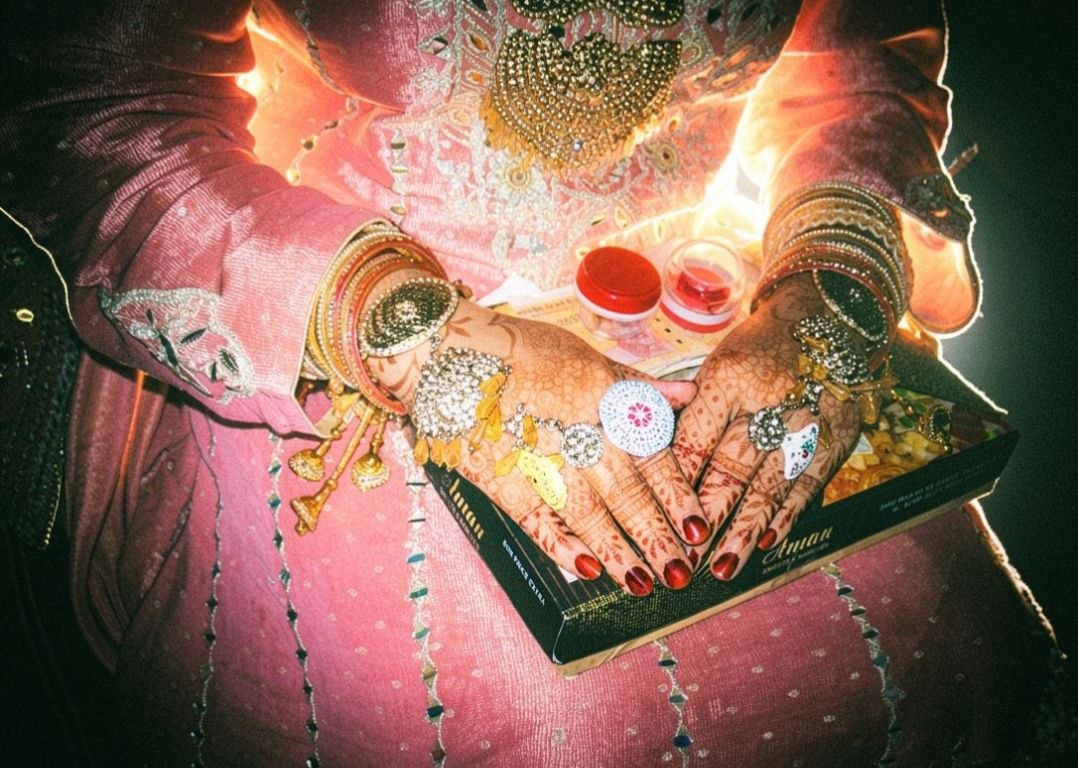 Bride's mehndi-adorned hands with gold jewellery